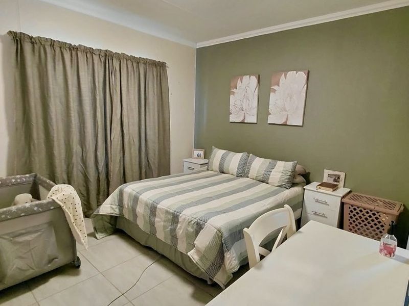 A functional bedroom featuring tiled flooring, a ceiling light fixture, and an accent wall, providing a comfortable and practical living space.