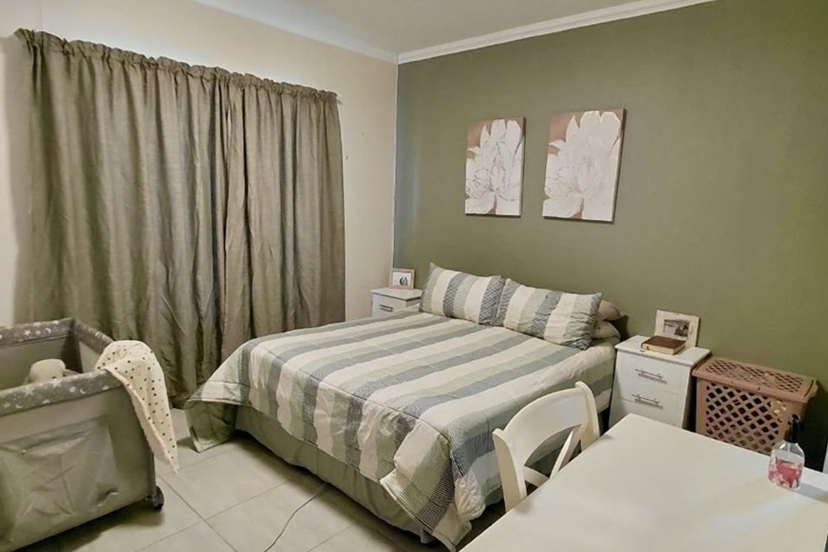 A functional bedroom featuring tiled flooring, a ceiling light fixture, and an accent wall, providing a comfortable and practical living space.