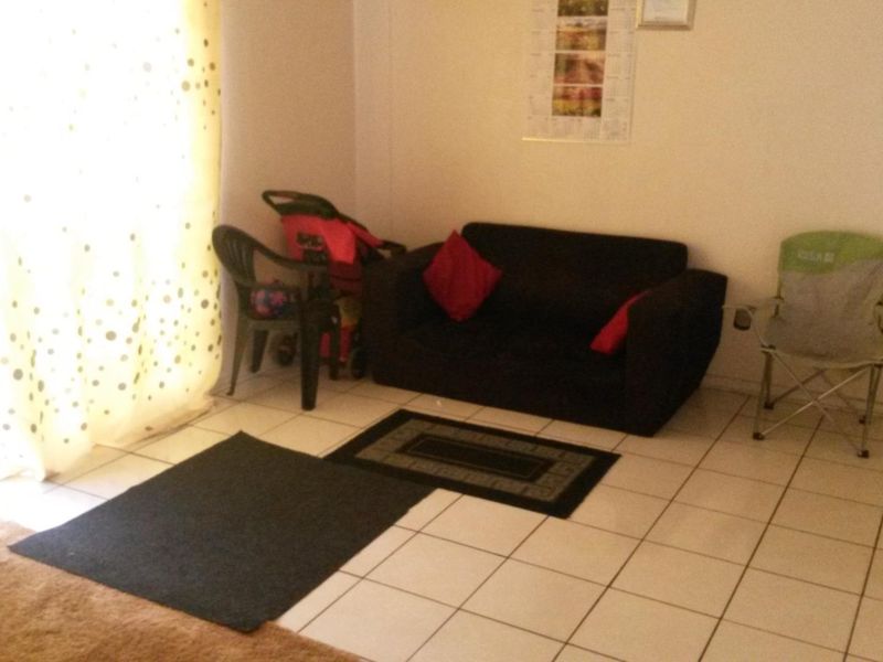 A living area featuring tiled flooring and natural light from a large window.