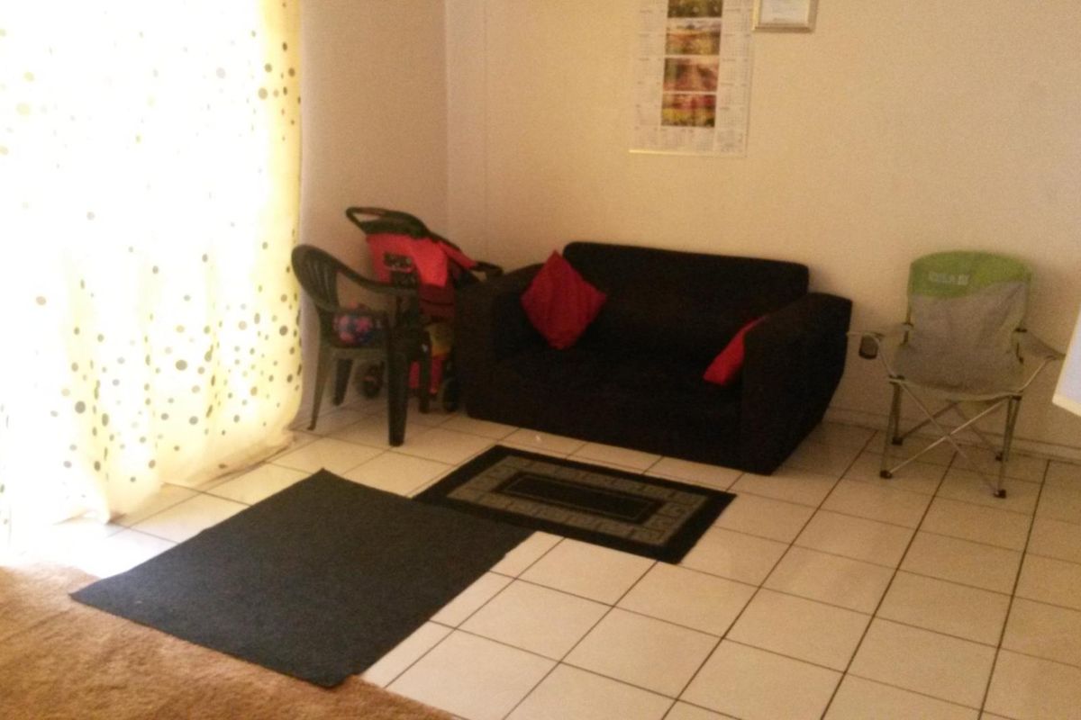 A living area featuring tiled flooring and natural light from a large window.