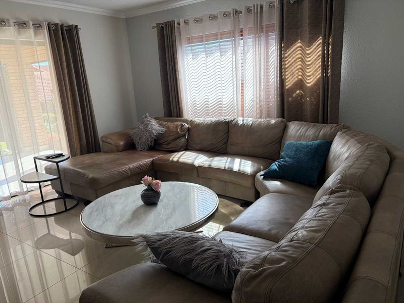 A comfortable living room featuring large sliding glass doors that provide natural light and access to the outdoor area, complemented by neutral tiled flooring.