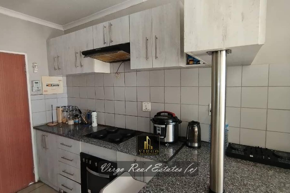 A functional kitchen featuring granite countertops, built-in cabinetry, a hob, and an extractor fan, offering a practical layout for daily meal preparation.