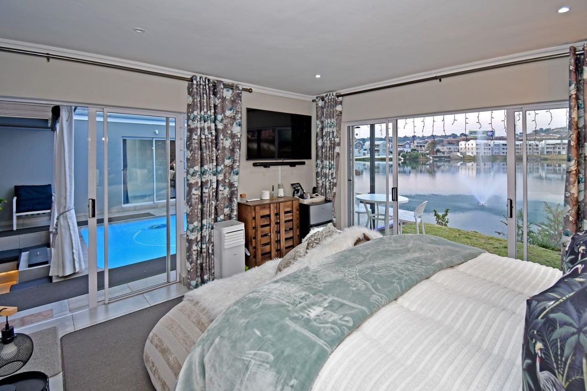 Spacious bedroom featuring large sliding glass doors that open to a private pool area and offer scenic lake views.