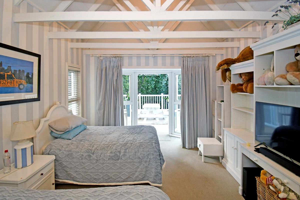 A bedroom featuring a vaulted ceiling with exposed beams, built-in shelving, and double doors opening onto an outdoor patio area.