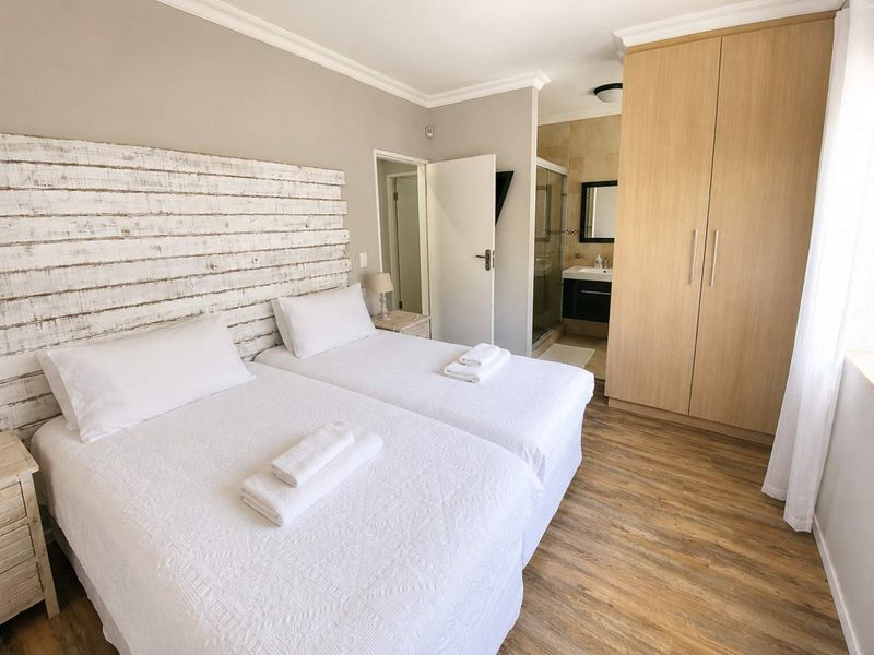 A well-maintained bedroom featuring laminate flooring, built-in wardrobes, and an attached en-suite bathroom with a modern vanity and shower enclosure.