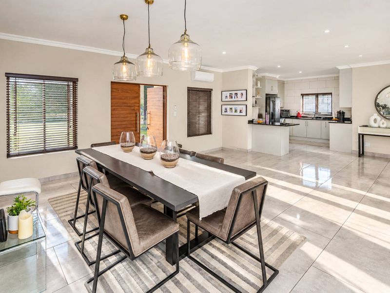 Spacious open-plan dining and kitchen area featuring polished porcelain tiles, modern cabinetry, granite countertops, and elegant pendant lighting.