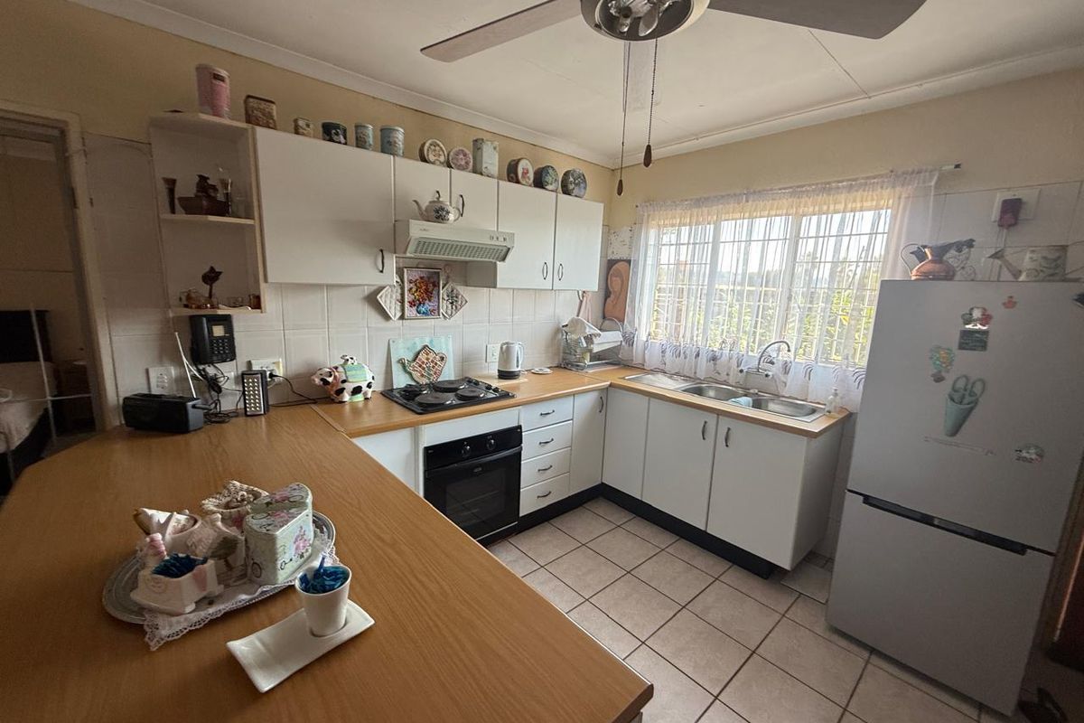 Functional kitchen featuring built-in cabinetry, laminate countertops, integrated oven and hob, double sink, and tiled flooring with a ceiling fan.