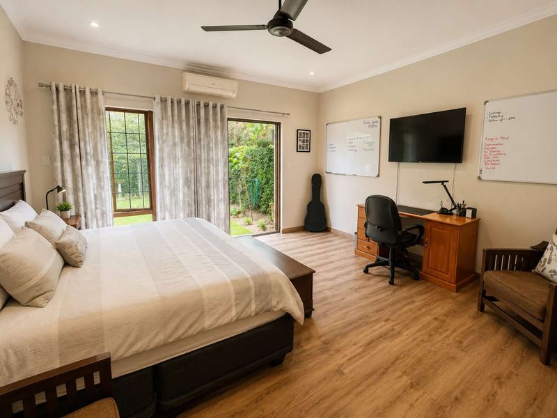 Spacious bedroom featuring laminate flooring, a ceiling fan, split-system air conditioning, and direct access to the garden through sliding glass doors.