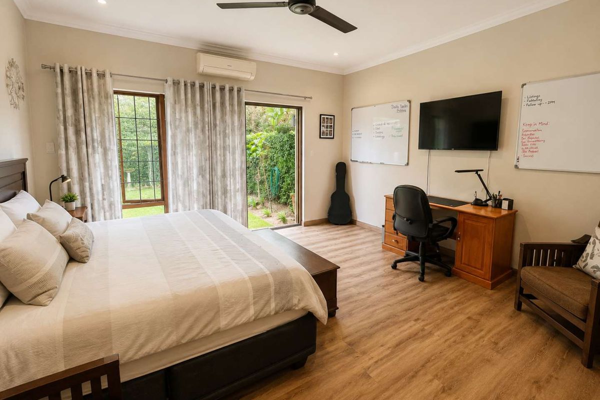 Spacious bedroom featuring laminate flooring, a ceiling fan, split-system air conditioning, and direct access to the garden through sliding glass doors.