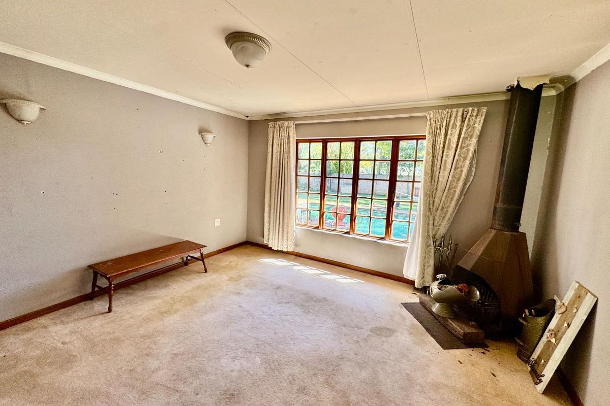 A living room featuring a built-in fireplace, large window with garden views, and wall-mounted lighting fixtures.