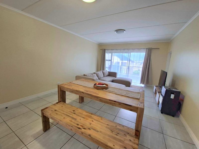 Open plan living and dining area featuring tiled flooring and a sliding glass door leading to a balcony.