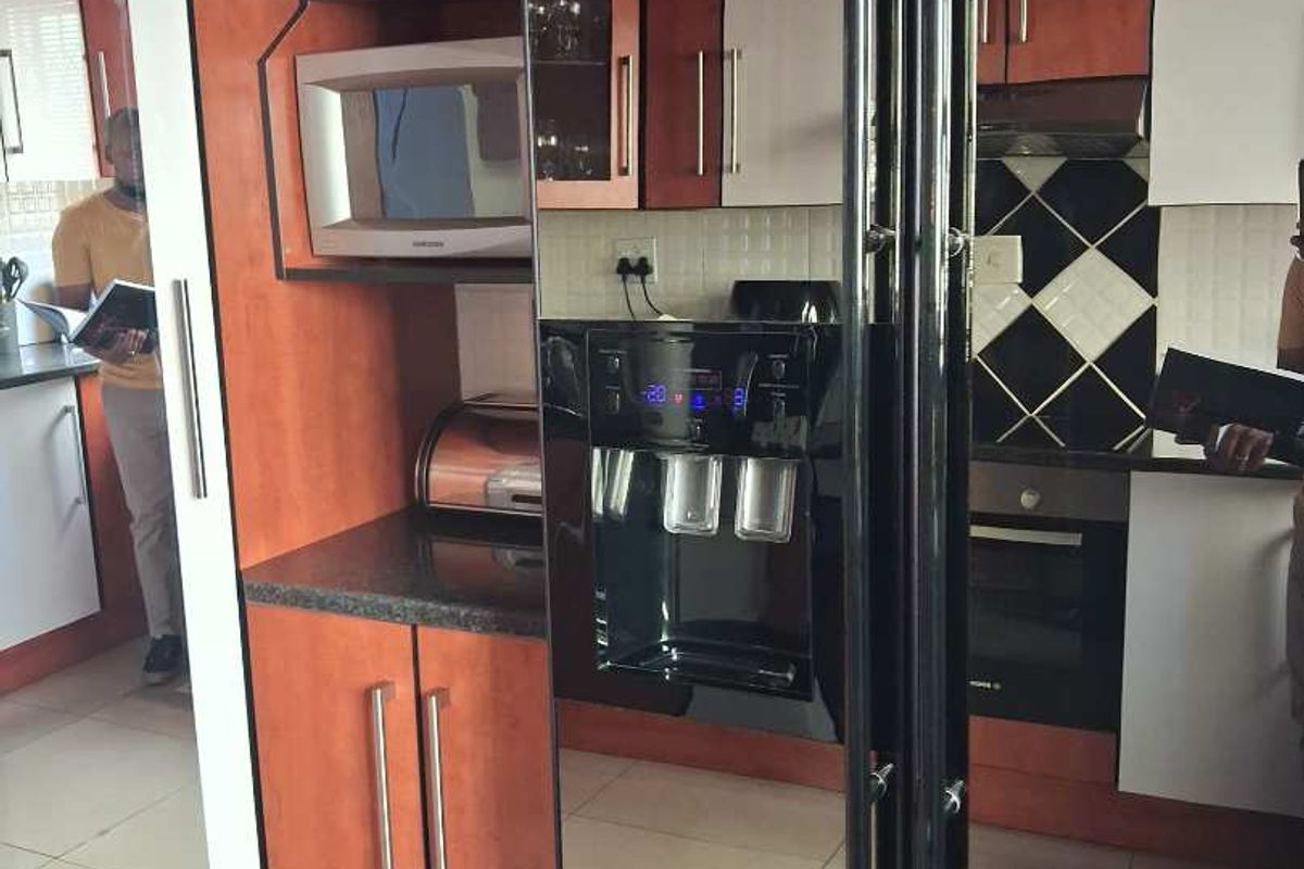 A functional kitchen featuring wood-toned cabinetry, dark granite countertops, a built-in oven, extractor fan, and a tiled backsplash.