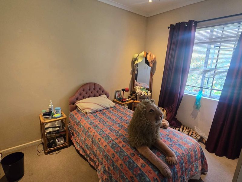 A standard bedroom featuring carpeted flooring, neutral wall finishes, and a window with installed curtain rods.