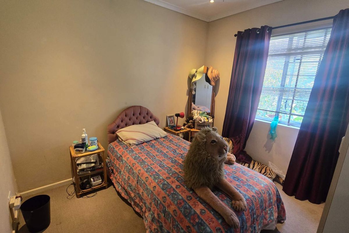 A standard bedroom featuring carpeted flooring, neutral wall finishes, and a window with installed curtain rods.