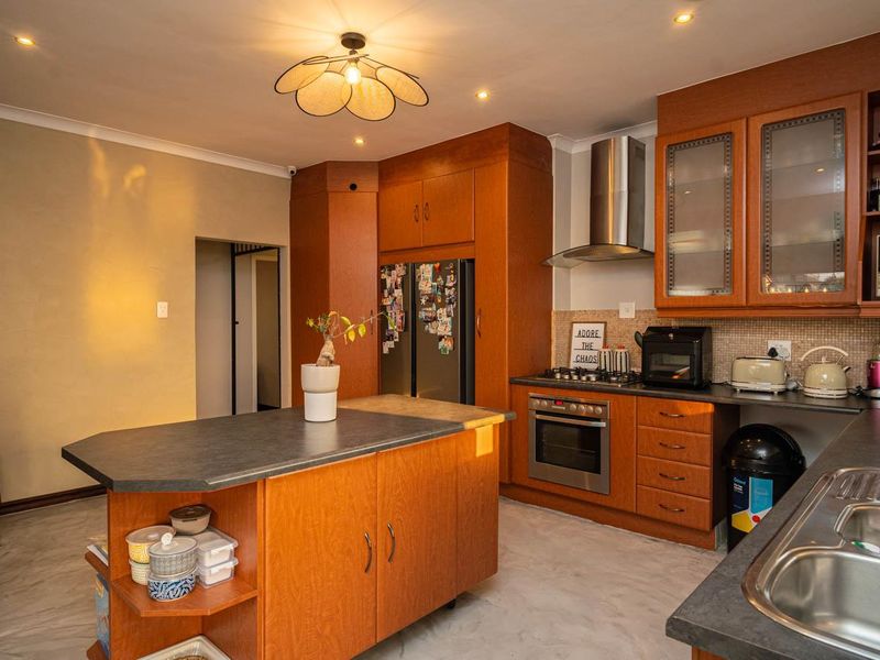 A functional kitchen featuring wood-toned cabinetry, a central island, stainless steel appliances, and a built-in wood-burning stove in the adjacent area.