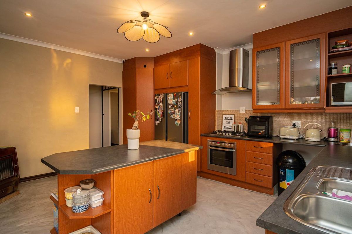 A functional kitchen featuring wood-toned cabinetry, a central island, stainless steel appliances, and a built-in wood-burning stove in the adjacent area.
