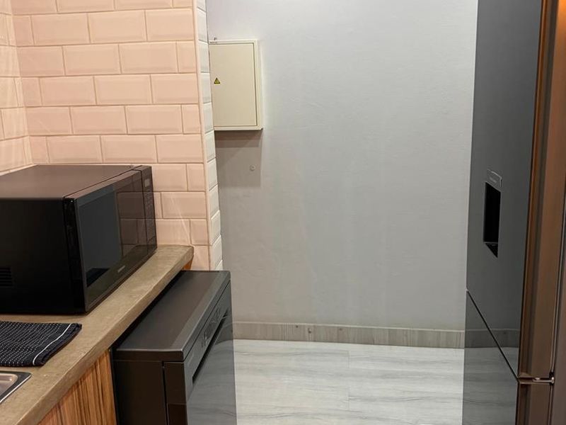 A functional kitchen area featuring a subway tile backsplash, laminate countertops, and built-in cabinetry with modern finishes.