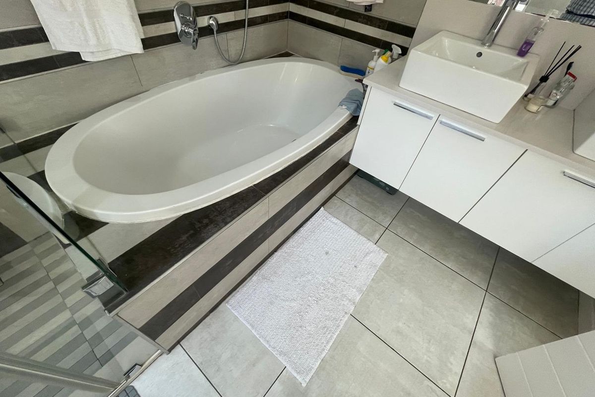 Modern bathroom featuring a built-in oval bathtub, a contemporary vessel sink vanity, and neutral floor-to-ceiling tiling.