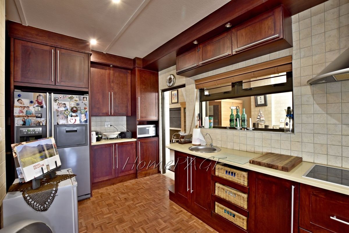 A functional kitchen featuring dark wood cabinetry, stone countertops, a built-in hob, and an integrated extractor fan with a pass-through window.