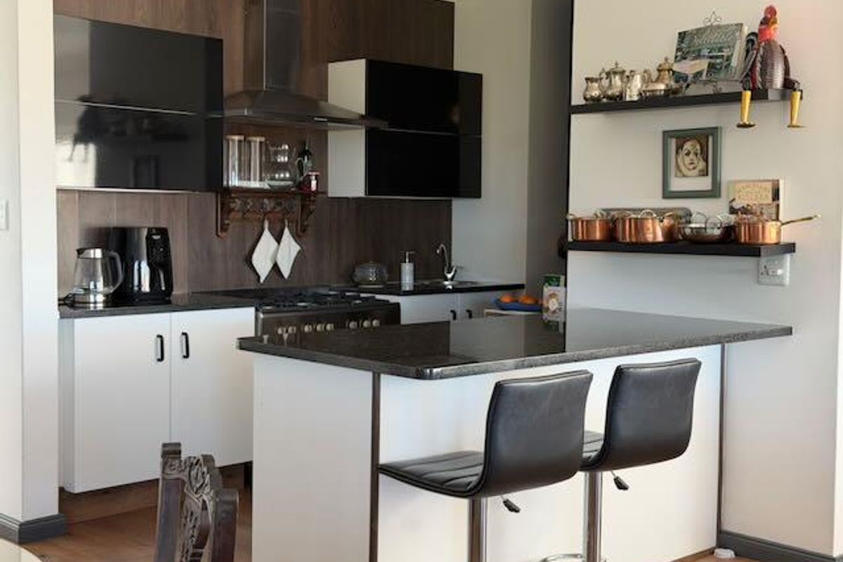Modern kitchen featuring dark wood-look cabinetry, contrasting white lower cabinets, a gas hob with stainless steel extractor fan, and a functional breakfast bar island.