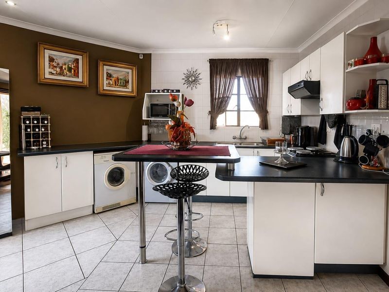 A functional kitchen featuring white cabinetry, dark countertops, tiled flooring, and integrated appliance spaces, offering a practical layout for daily meal preparation.