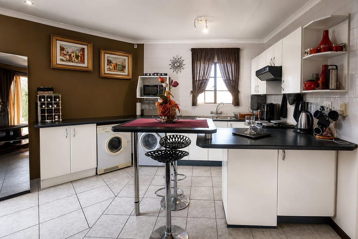 A functional kitchen featuring white cabinetry, dark countertops, tiled flooring, and integrated appliance spaces, offering a practical layout for daily meal preparation.