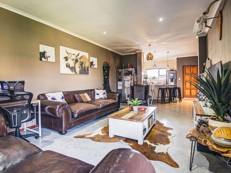 Spacious open-plan living area featuring polished concrete floors, recessed lighting, and a seamless transition to the kitchen breakfast bar area.