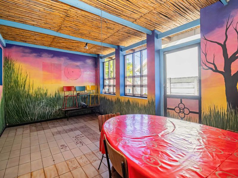 Enclosed patio area featuring a unique bamboo ceiling, tiled flooring, and large windows, offering a versatile space for outdoor dining or relaxation.