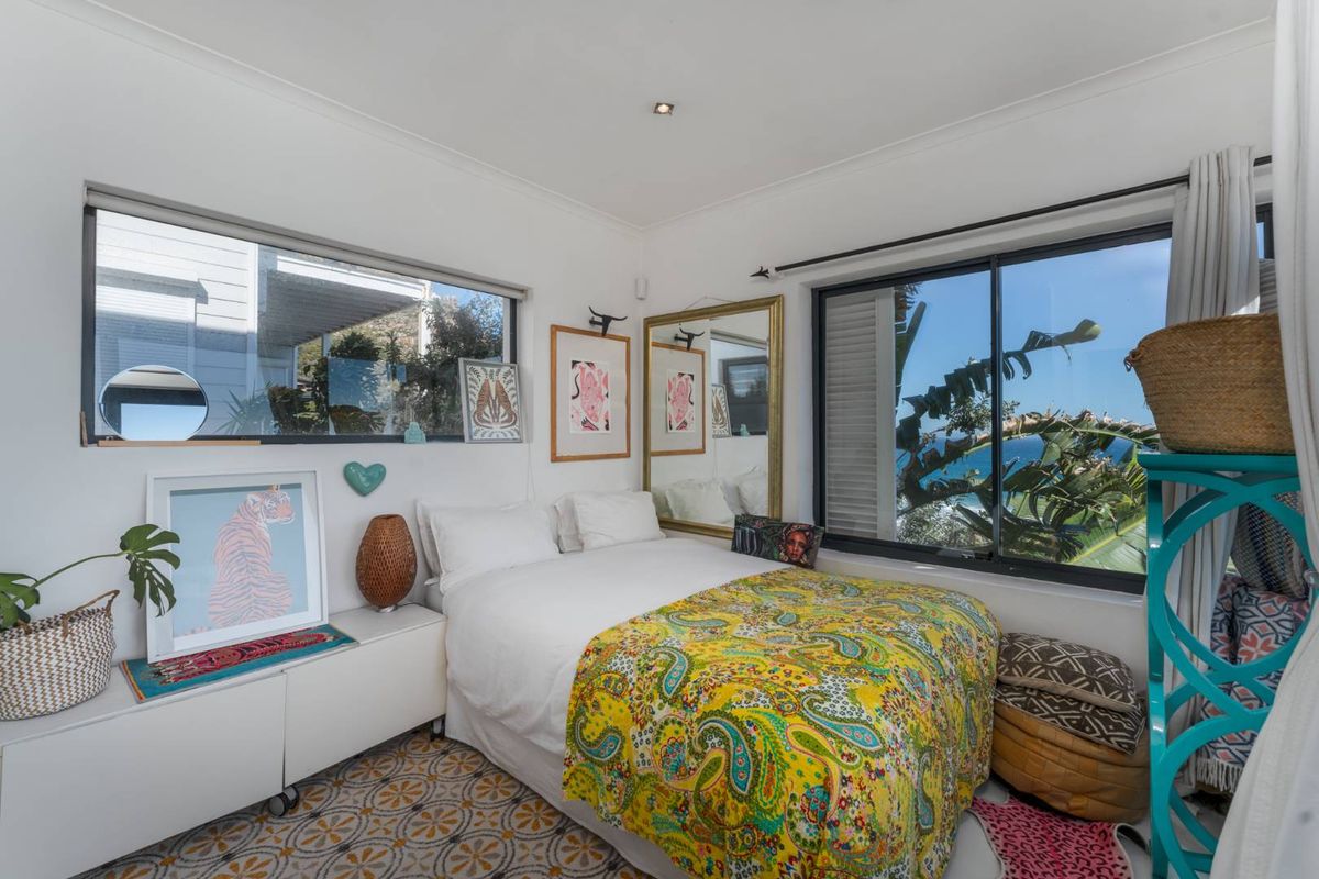 A bright bedroom featuring patterned floor tiles, recessed downlights, and large sliding windows offering natural light and scenic views.