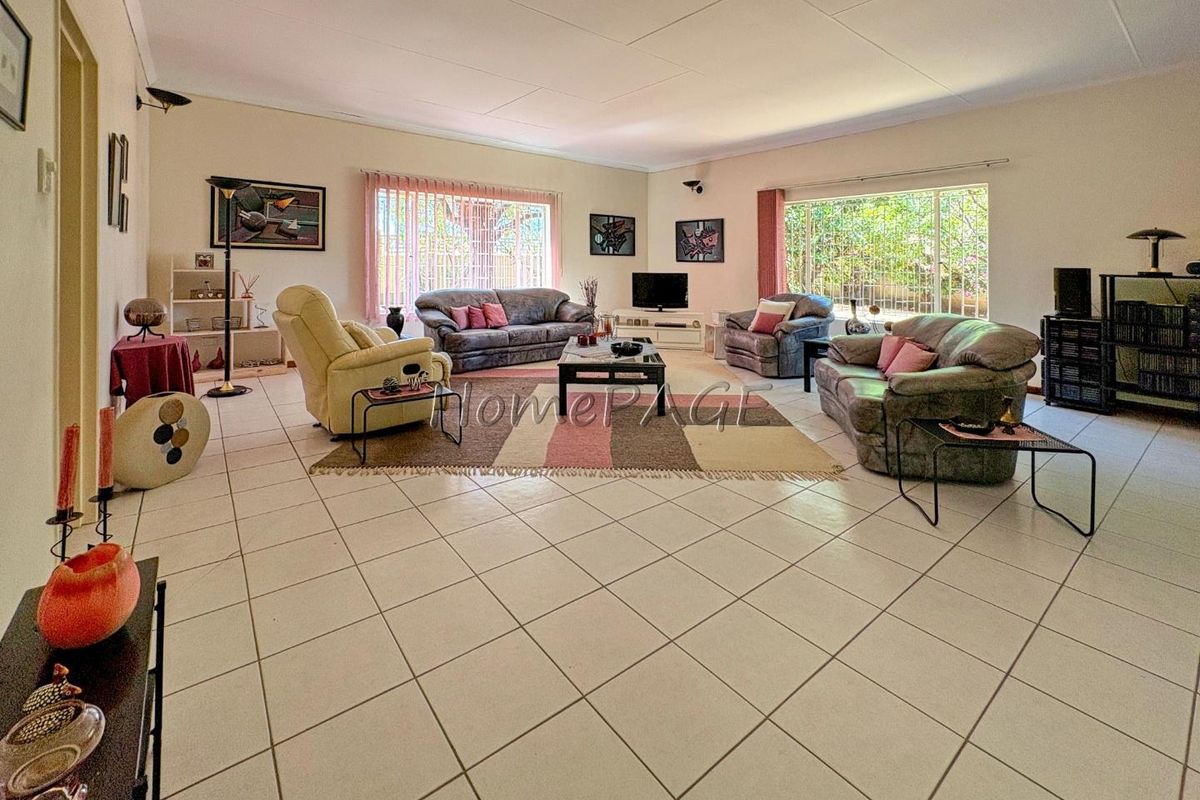 Spacious living room featuring large windows, tiled flooring, and neutral wall finishes, offering a bright and open area for relaxation.