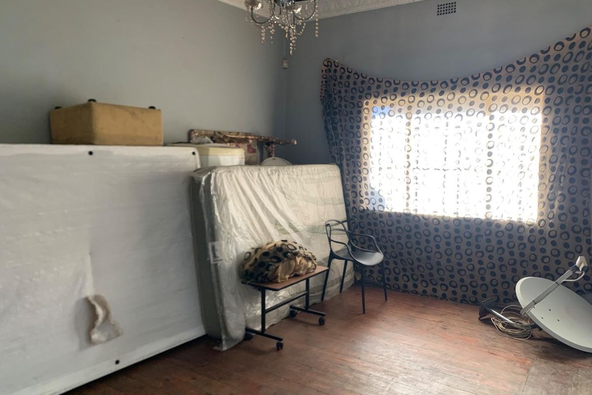 A bedroom featuring original timber flooring, decorative ceiling cornice, and a central light fixture, offering a blank canvas for renovation.