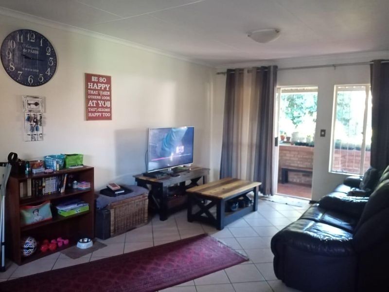 A living room featuring tiled flooring and a sliding glass door providing access to an outdoor patio area.