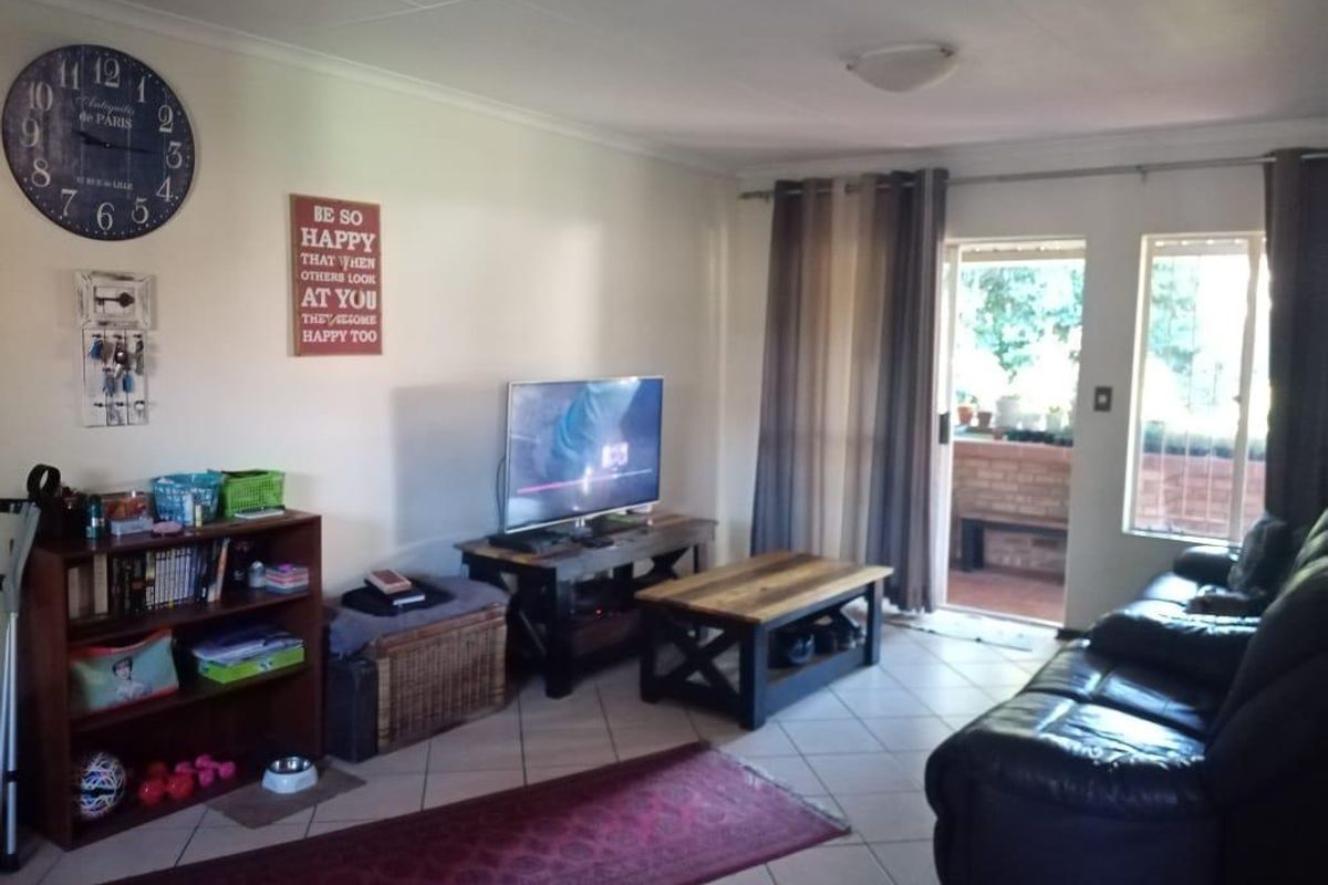 A living room featuring tiled flooring and a sliding glass door providing access to an outdoor patio area.
