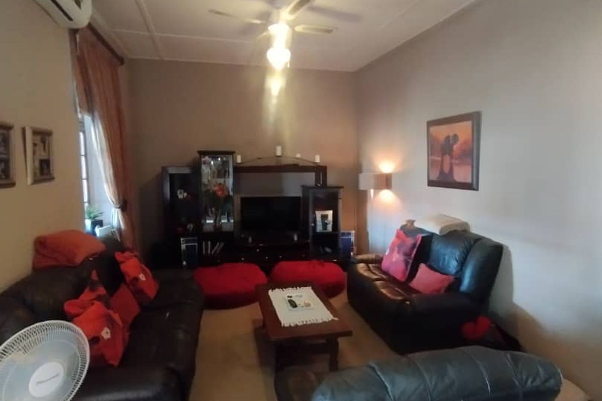 A comfortable living room featuring a ceiling fan, wall-mounted air conditioning unit, and neutral wall finishes.