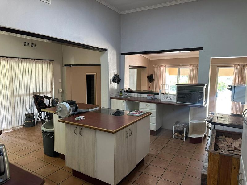 Open-plan kitchen area featuring a central island, tiled flooring, and direct access to adjacent living spaces through large openings.