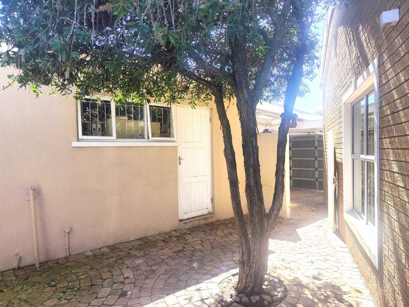 A private rear courtyard featuring paved flooring, brick wall finishes, and access to a garage, providing a functional outdoor space.