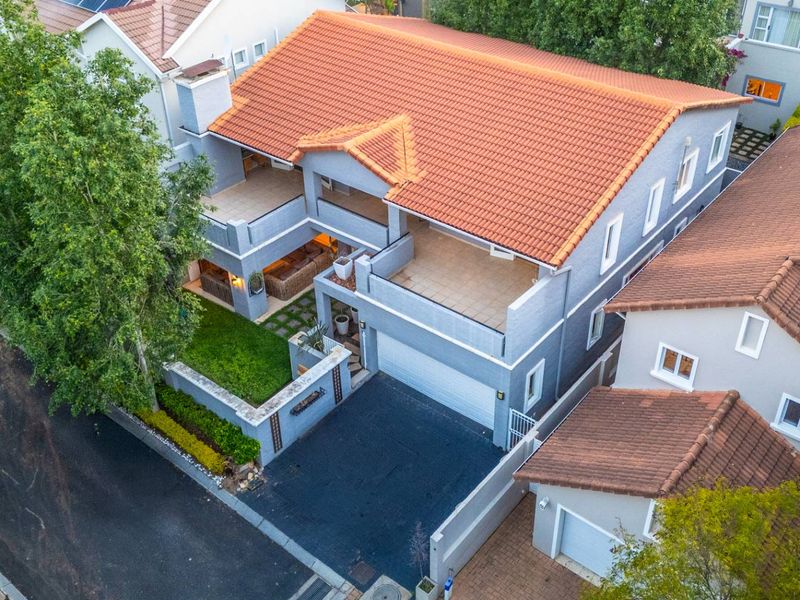 Aerial view of a two-story residential property featuring a terracotta tile roof, solar panels, a double garage, and multiple balconies.