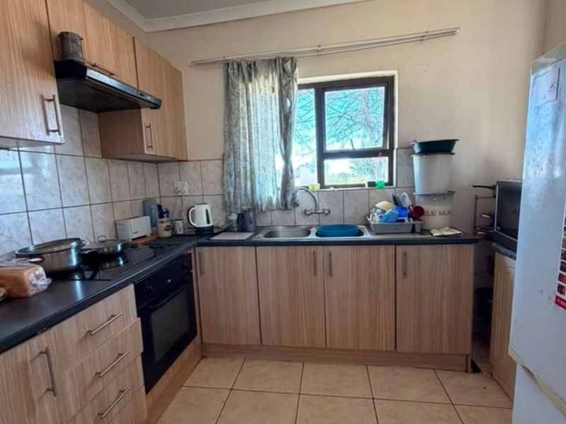 Functional kitchen featuring laminate cabinetry, built-in oven, electric hob, extractor fan, and tiled flooring with a double bowl sink.