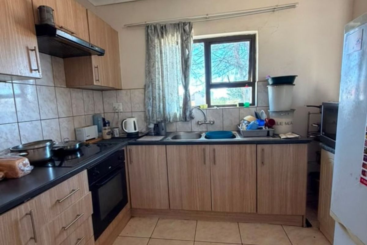 Functional kitchen featuring laminate cabinetry, built-in oven, electric hob, extractor fan, and tiled flooring with a double bowl sink.