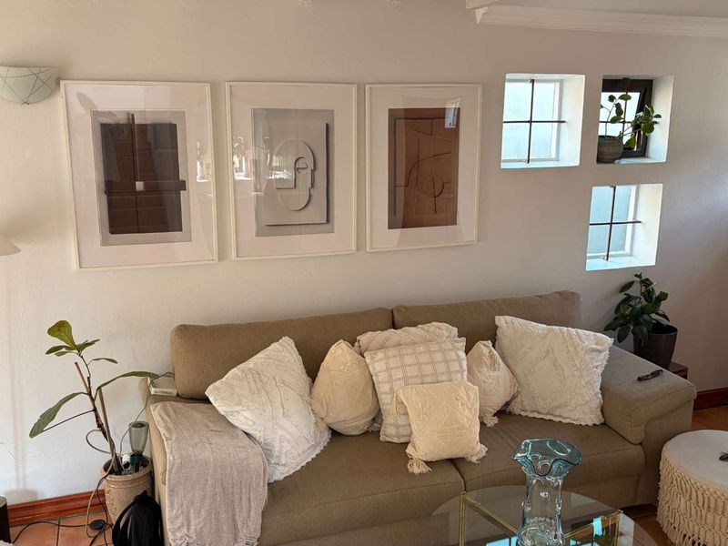 A cozy living room area featuring tiled flooring, wall-mounted lighting, and small square windows providing natural light.