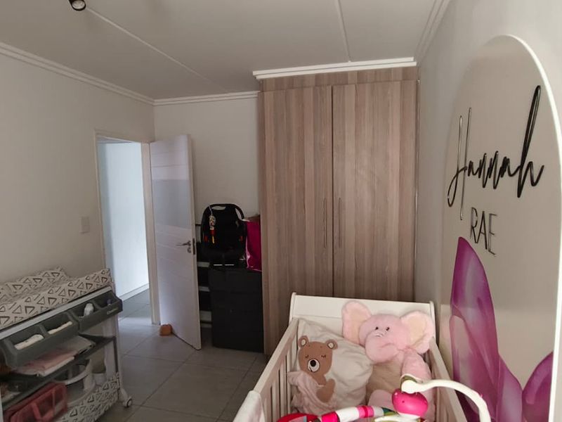 A bedroom featuring tiled flooring and a built-in wooden wardrobe, providing functional storage space within the apartment.