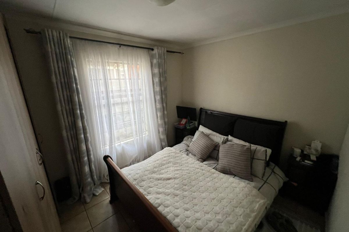 A functional bedroom featuring tiled flooring, a built-in wardrobe, and a window with installed curtain rods.