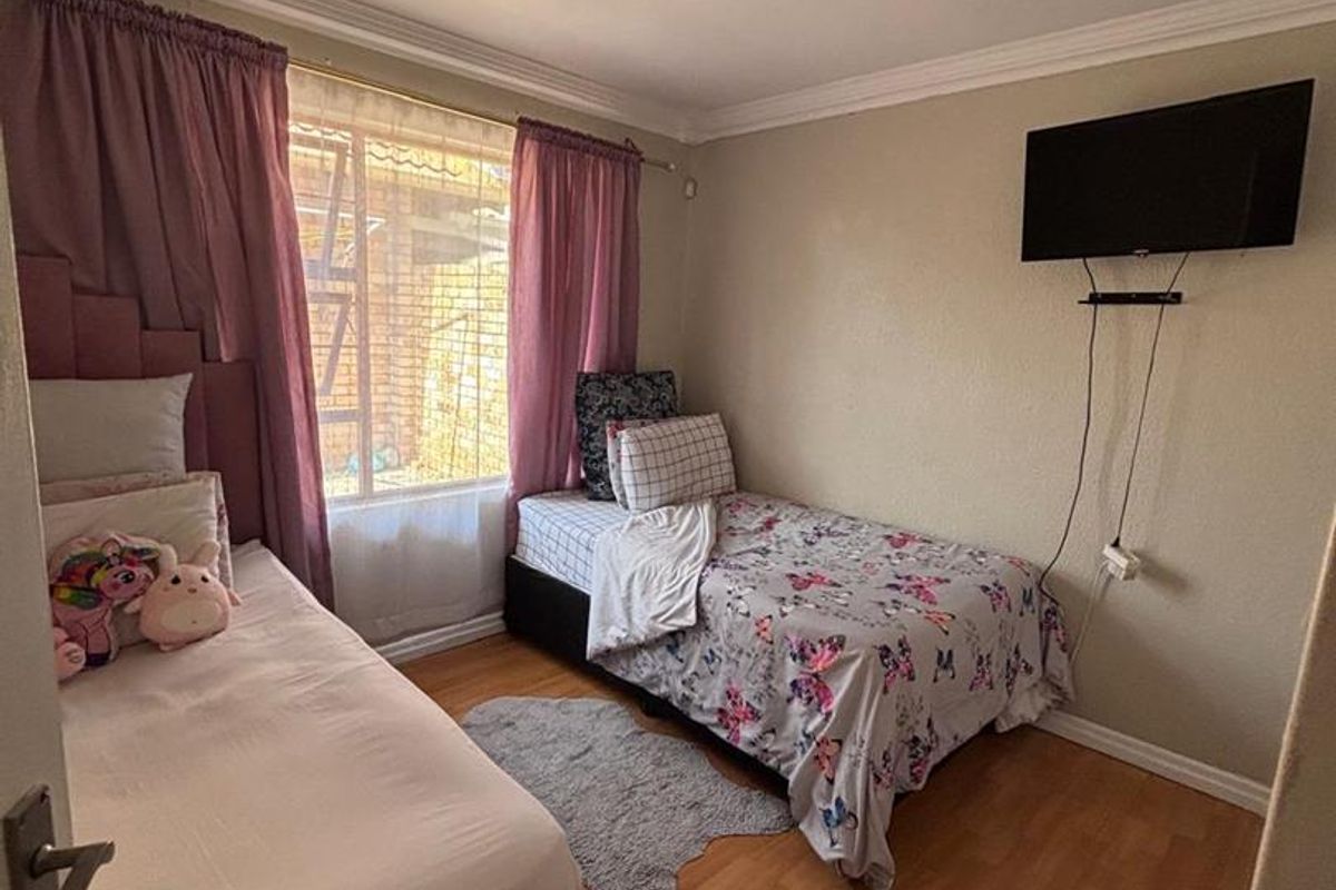 A bedroom featuring laminate flooring, crown molding, and a window with curtain rails.