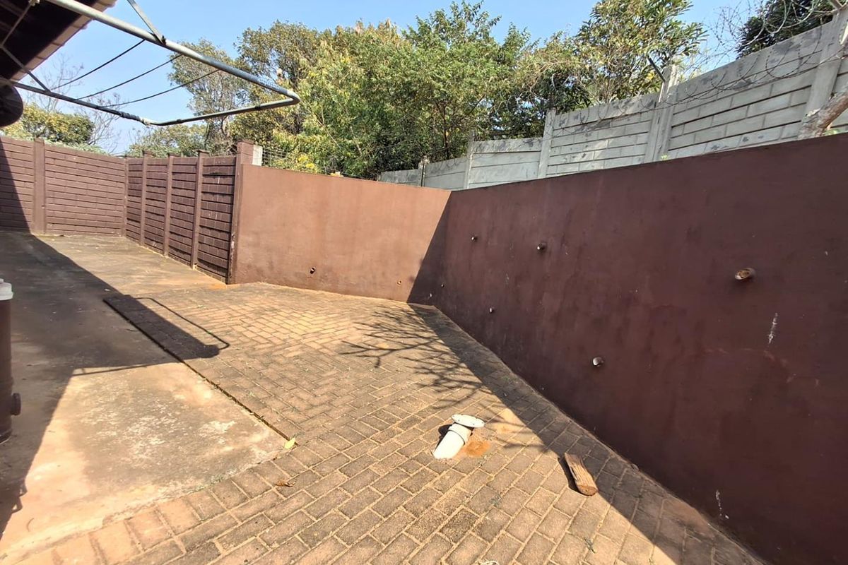 A paved rear courtyard area enclosed by perimeter walls with security razor wire and a wall-mounted clothesline.