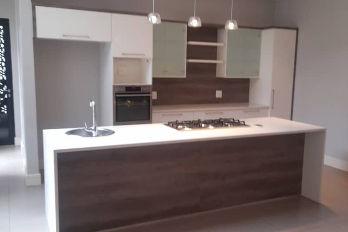Modern kitchen featuring a central island with a built-in gas hob, integrated oven, sleek cabinetry, and tiled flooring.