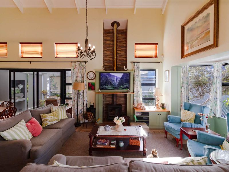 Spacious living room featuring a high vaulted ceiling with exposed beams, a central wood-burning fireplace with stone detailing, and large sliding doors to the patio.