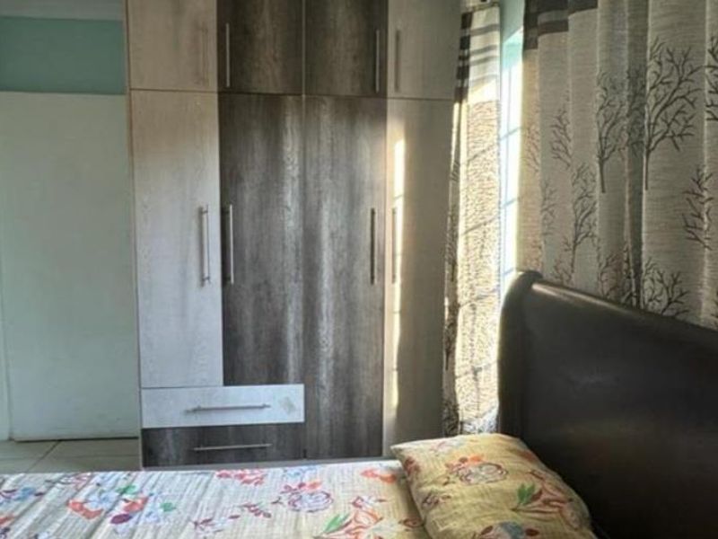 A bedroom featuring a modern two-tone built-in wardrobe and tiled flooring, providing functional storage space.
