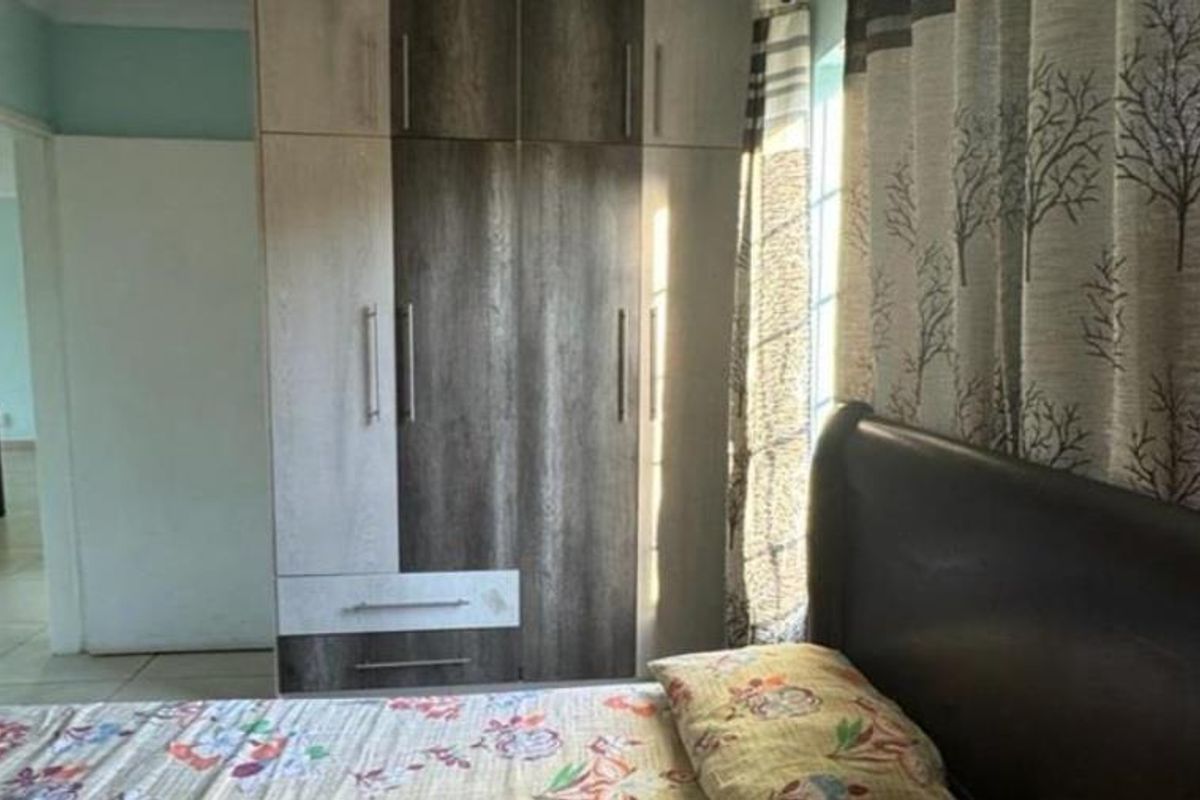 A bedroom featuring a modern two-tone built-in wardrobe and tiled flooring, providing functional storage space.