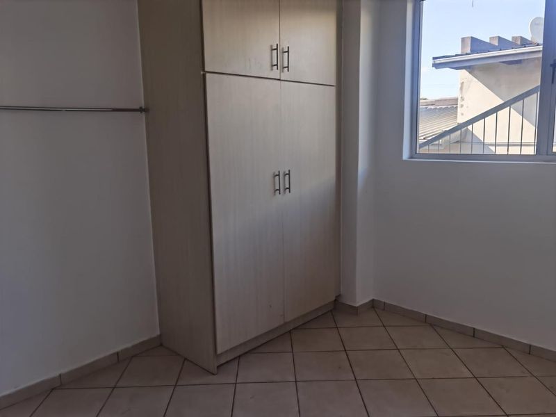 A clean, empty bedroom featuring neutral tiled flooring and a built-in wardrobe, offering a blank canvas for personalization.