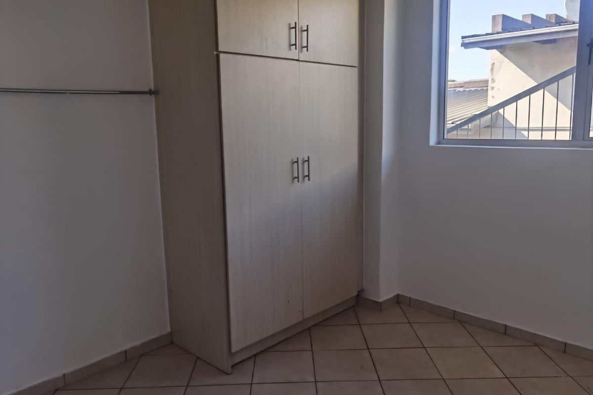 A clean, empty bedroom featuring neutral tiled flooring and a built-in wardrobe, offering a blank canvas for personalization.